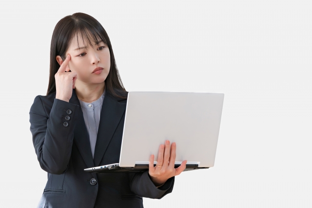 パソコンを手に悩む女性