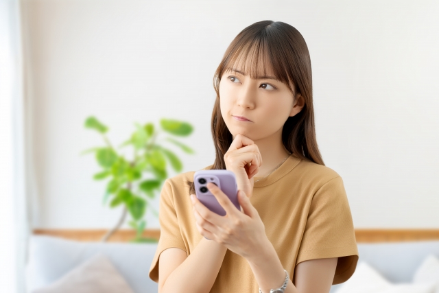 スマホを片手に悩む女性